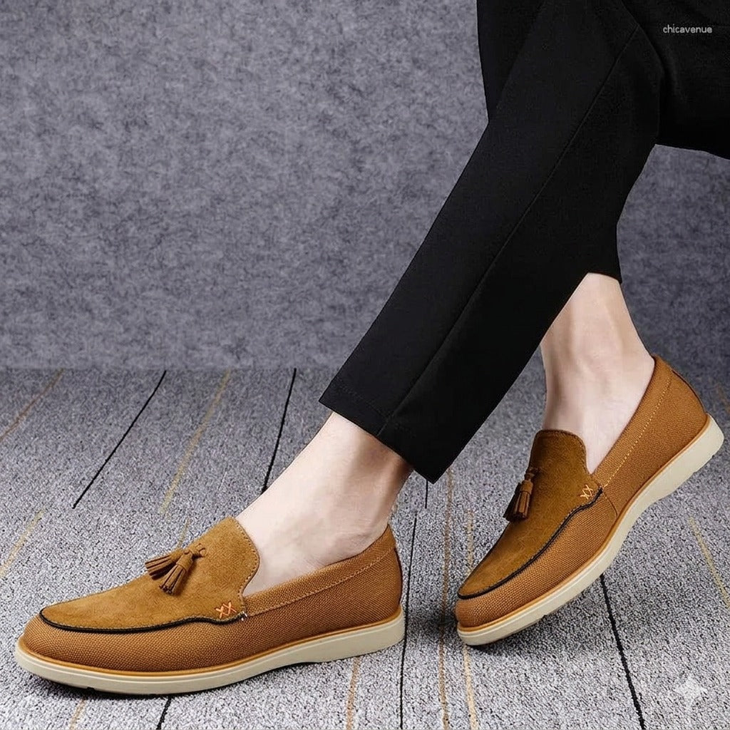 Brown loafers with tassels worn by a person on a gray floor.