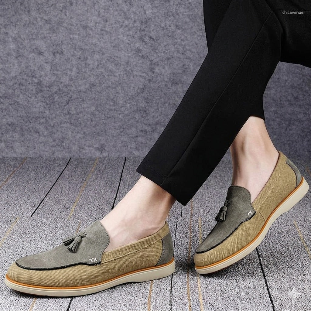 Brown loafers with tassels worn by a person on a wooden floor.