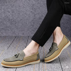 Brown loafers with tassels worn by a person on a wooden floor.