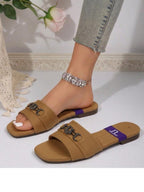 Brown sandals with chain details worn by a person, on a light background.