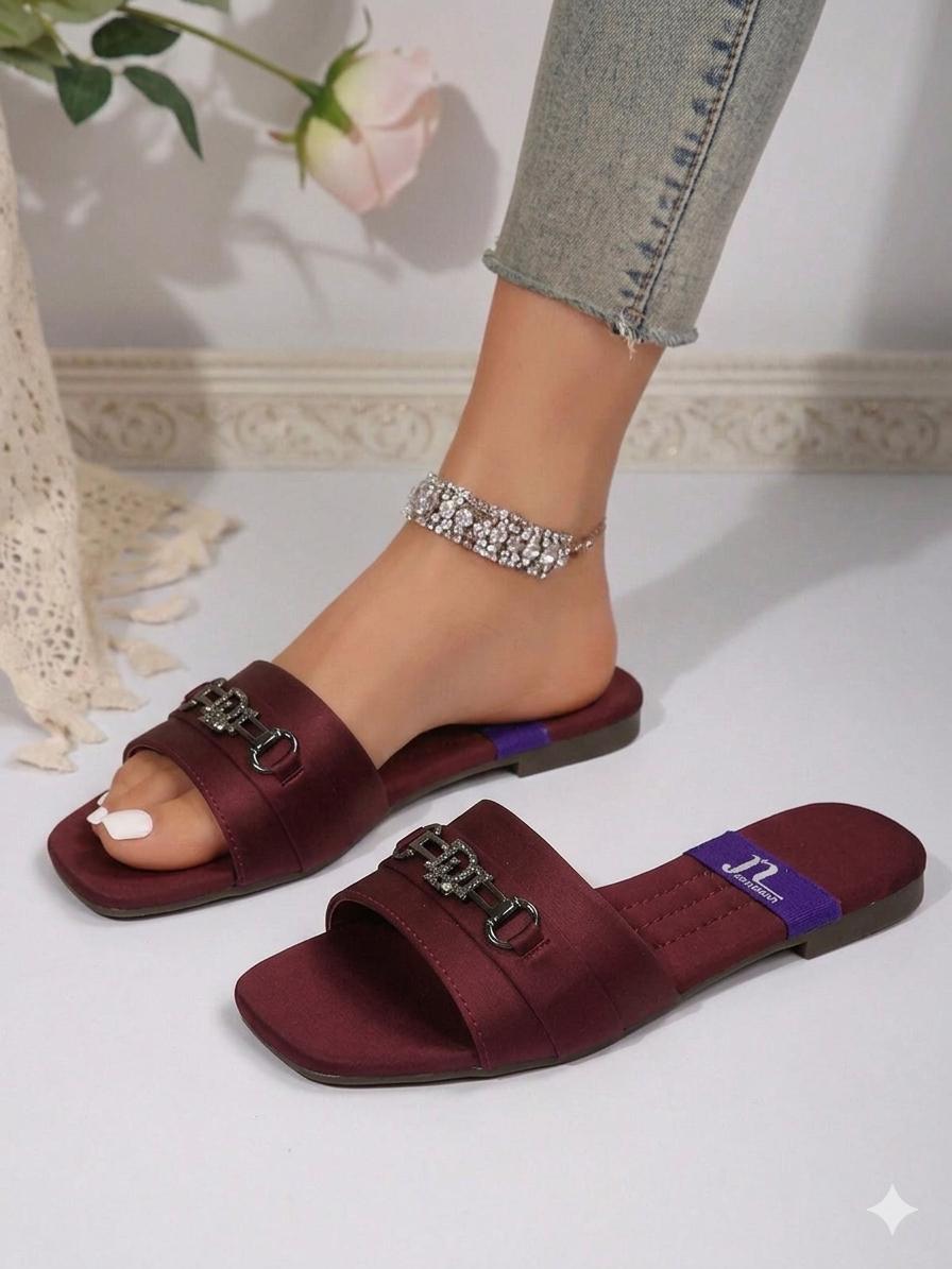 Burgundy sandals with chain details worn by a person, with a light background.