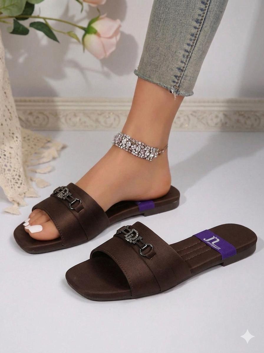 Brown sandals with purple accents worn by a person on a light background