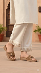 Person wearing beige sandals and white pants with a blurred background