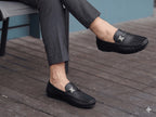Person wearing black loafers on a wooden floor