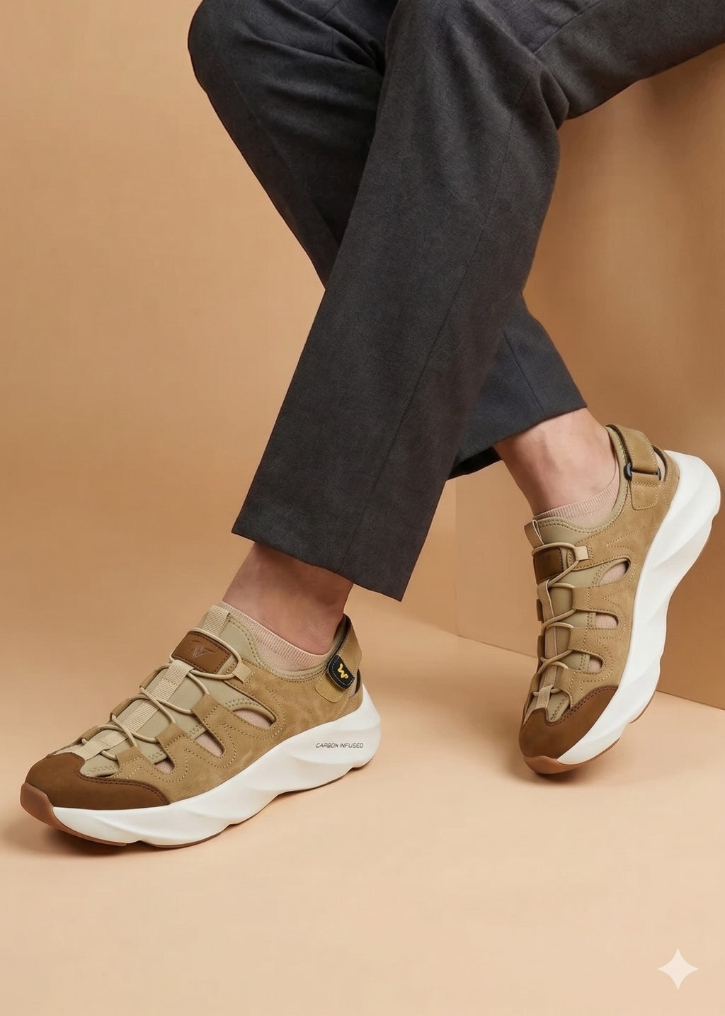 Brown sneakers worn with dark pants on a beige background