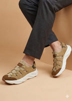 Brown sneakers worn with dark pants on a beige background