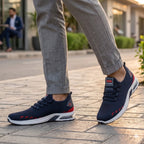 Navy and red sneakers worn on a paved walkway with a blurred background