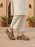 Person wearing brown sandals with a light-colored outfit in an outdoor setting.