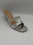 Silver sandal with clear heel and embellishments on a gray background