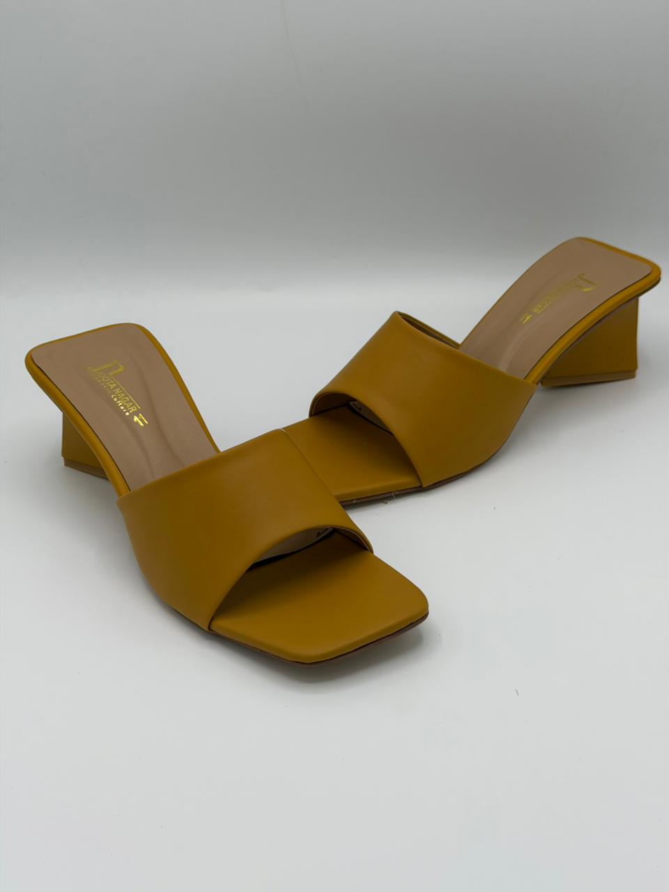 Pair of mustard yellow high-heeled sandals on a light gray background