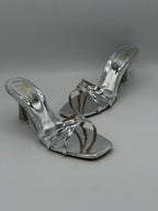 Pair of silver high-heeled sandals on a gray background