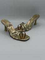 Gold high-heeled sandals on a gray background