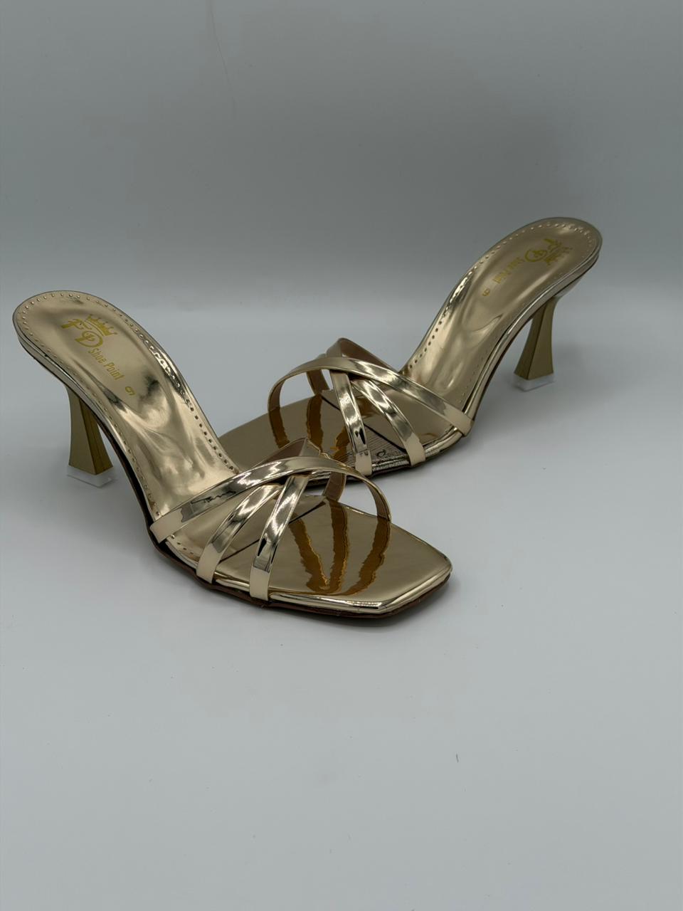 Gold high-heeled sandals on a gray background