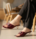 Maroon high-heeled sandals worn indoors with a blurred background