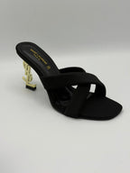 Black sandal with gold heel on a light gray background