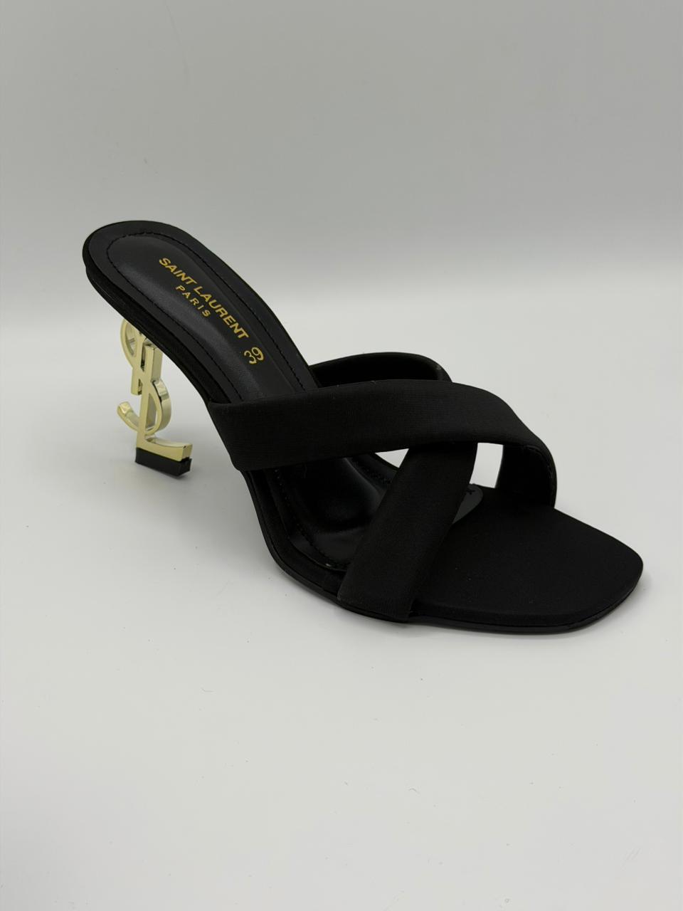 Black sandal with gold heel on a light gray background