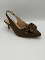 Brown high-heeled shoe with decorative embellishment on a light gray background