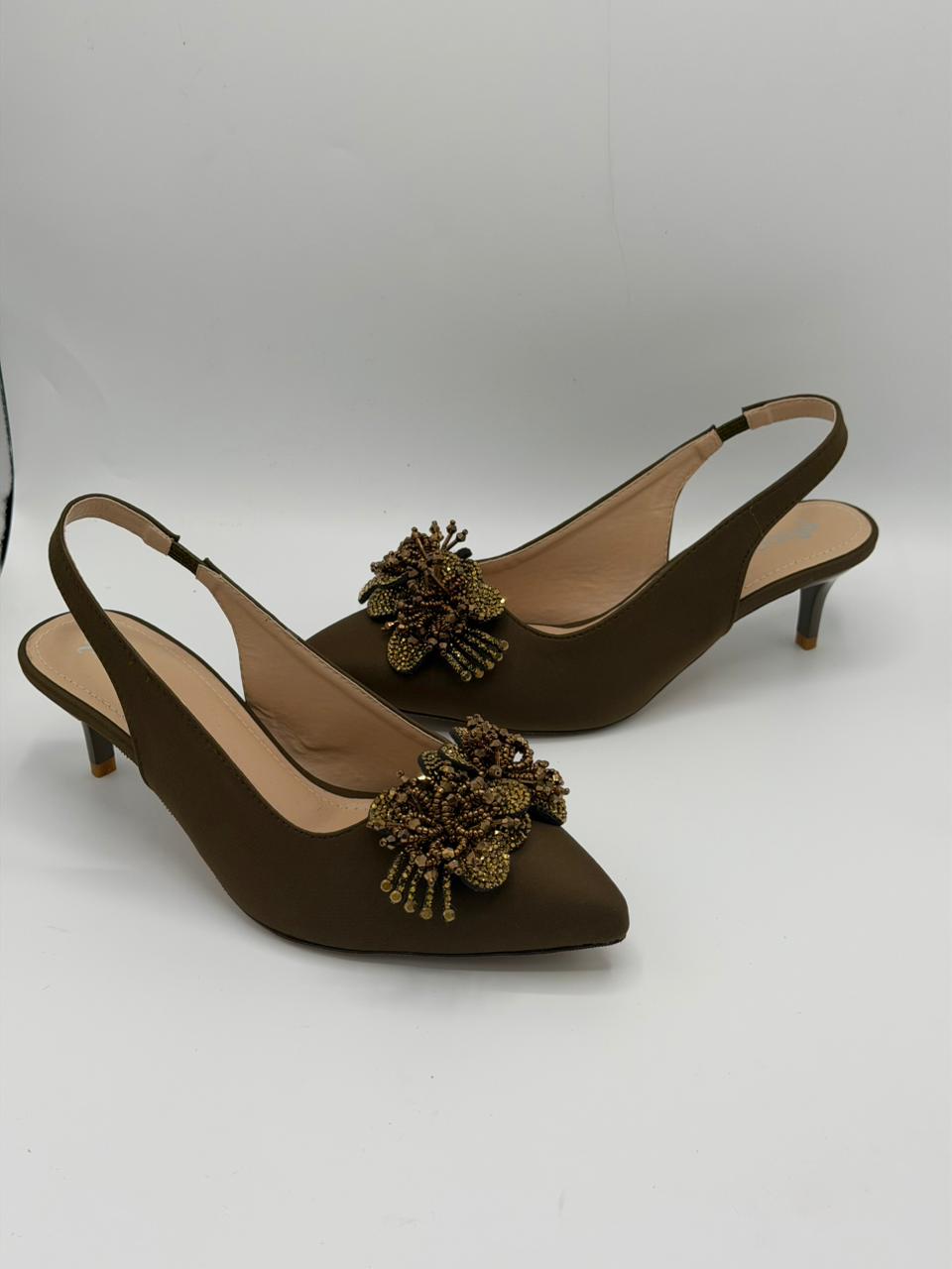 Brown high-heeled shoes with decorative elements on a white background