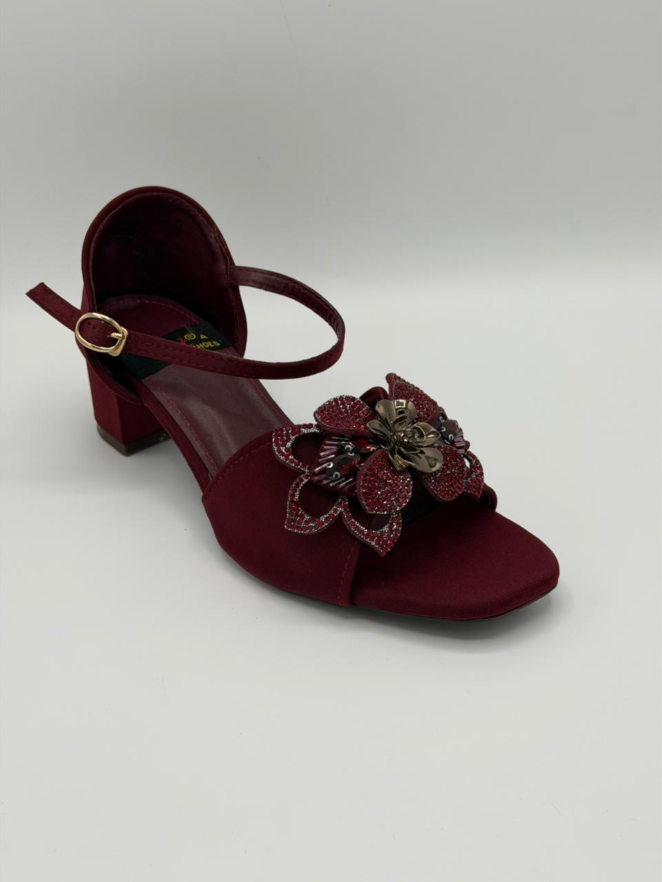 Maroon sandal with decorative flower on a light gray background