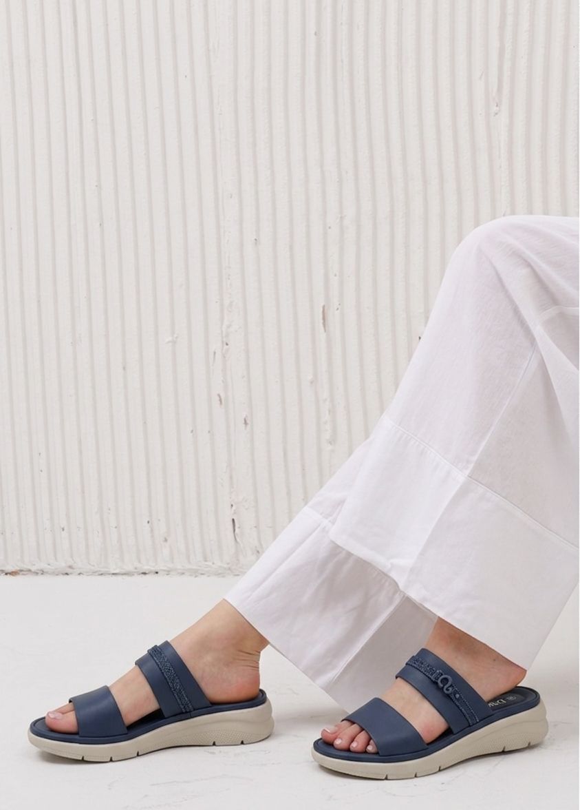 Navy sandals worn with white pants against a light background