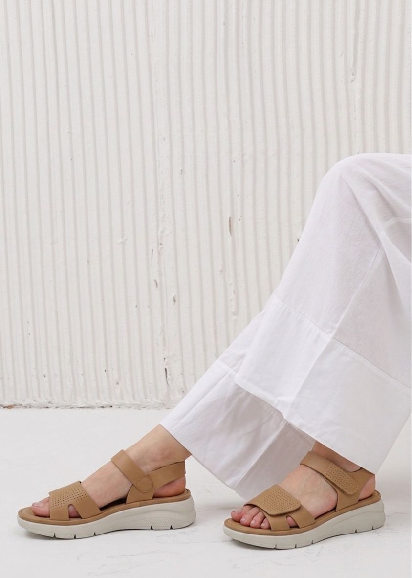 Tan sandals worn with white pants against a light background