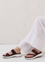 Person wearing brown sandals with white soles on a light background