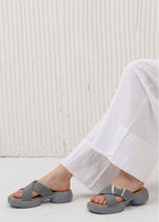 Gray sandals worn with white pants against a light background
