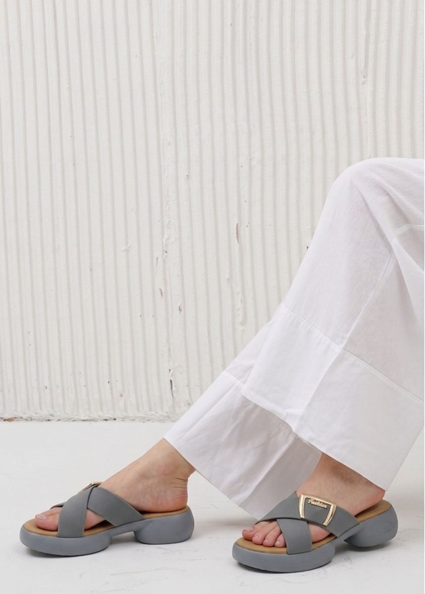 Gray sandals worn with white pants against a light background