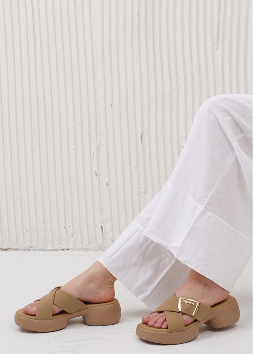 Person wearing tan sandals with a white background