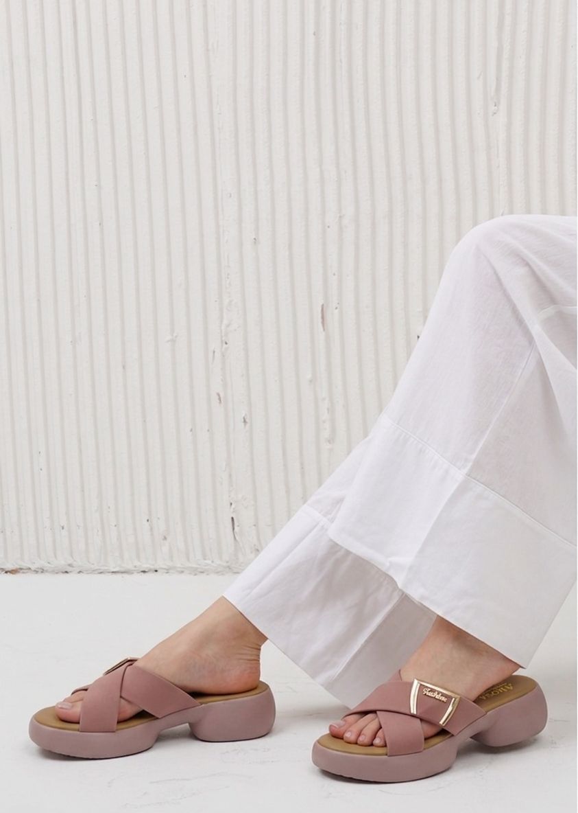 Person wearing pink sandals with white pants against a light background