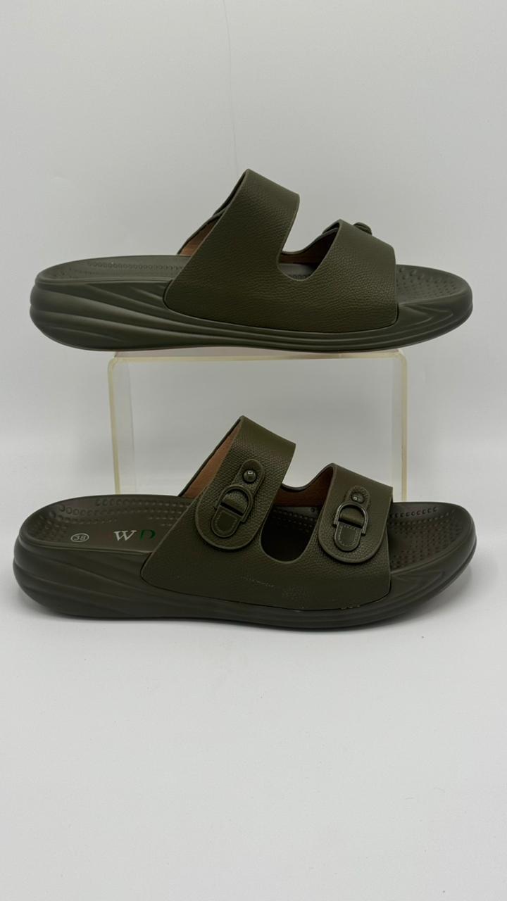 Pair of green sandals on a clear stand against a white background