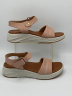 Pair of pink sandals with brown soles on a white background
