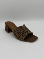 Brown sandal with decorative straps on a gray background