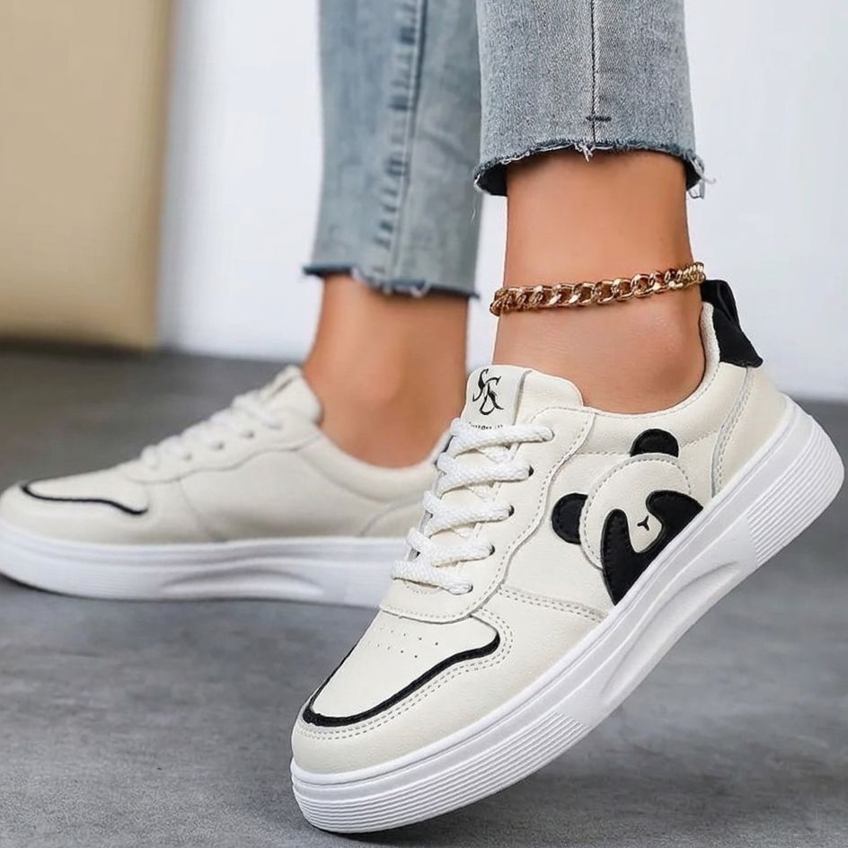 White sneakers with black accents worn by a person on a neutral background