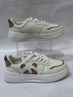 White sneakers with brown accents on a clear stand against a white background