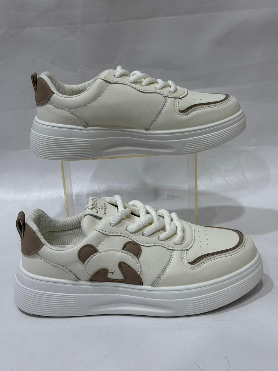 White sneakers with brown accents on a clear stand against a white background