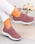 A pair of women's slip-on sneakers in a dusty rose pink color with white soles, shown on a model wearing white pants. The shoes feature a textured knit upper and a ribbed synthetic toe box, with the brand name 'Kate' visible on the side of the uppers.