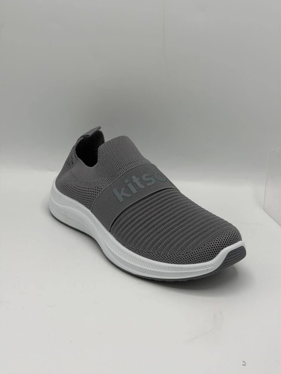 A gray slip-on sneaker with a textured knit upper, a white midsole, and a dark gray outsole, shown on a light gray background.