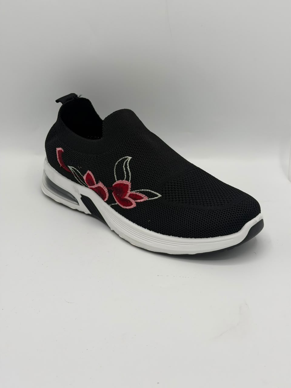 A black slip-on mesh sneaker with a white sole and red floral embroidery on the side, shown against a plain white background.