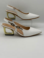 A pair of white pointed-toe slingback heels with a unique gold geometric block heel and a decorative chain detail on the ankle strap, displayed on a light gray background.