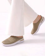 A person wearing off-white wide-leg trousers and beige slip-on knit sneakers with white soles, shown against a clean white studio background.