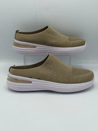 A pair of slip-on wedge sneakers in olive green with textured knit uppers and thick white platform soles, displayed on a light gray background with one shoe on a clear stand.