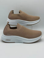 A pair of slip-on athletic sneakers in a warm taupe-brown color with textured knit uppers and thick white midsoles, displayed on a light gray background.