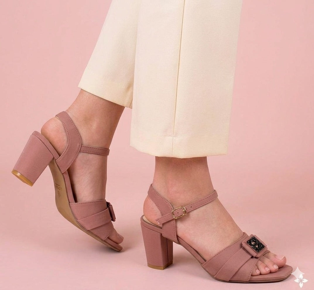 Pink block-heel sandals worn with light-colored pants on a pink background
