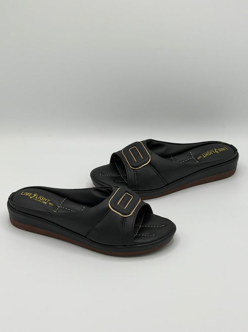 Black sandals with gold buckles on a gray background