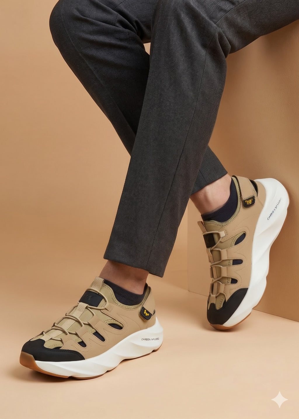 Beige sneakers with black accents worn with dark pants on a beige background
