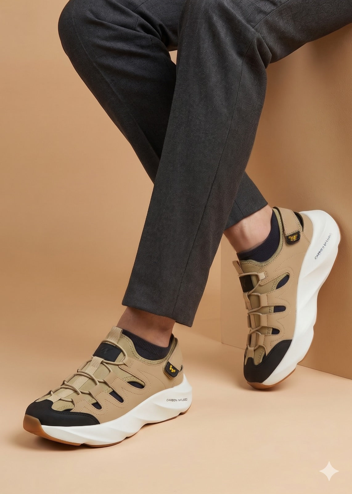 Beige sneakers with black accents worn with dark pants on a beige background