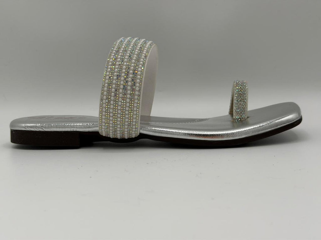 Silver sandal with beaded strap on a gray background