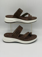 Brown sandals with white soles on a gray background