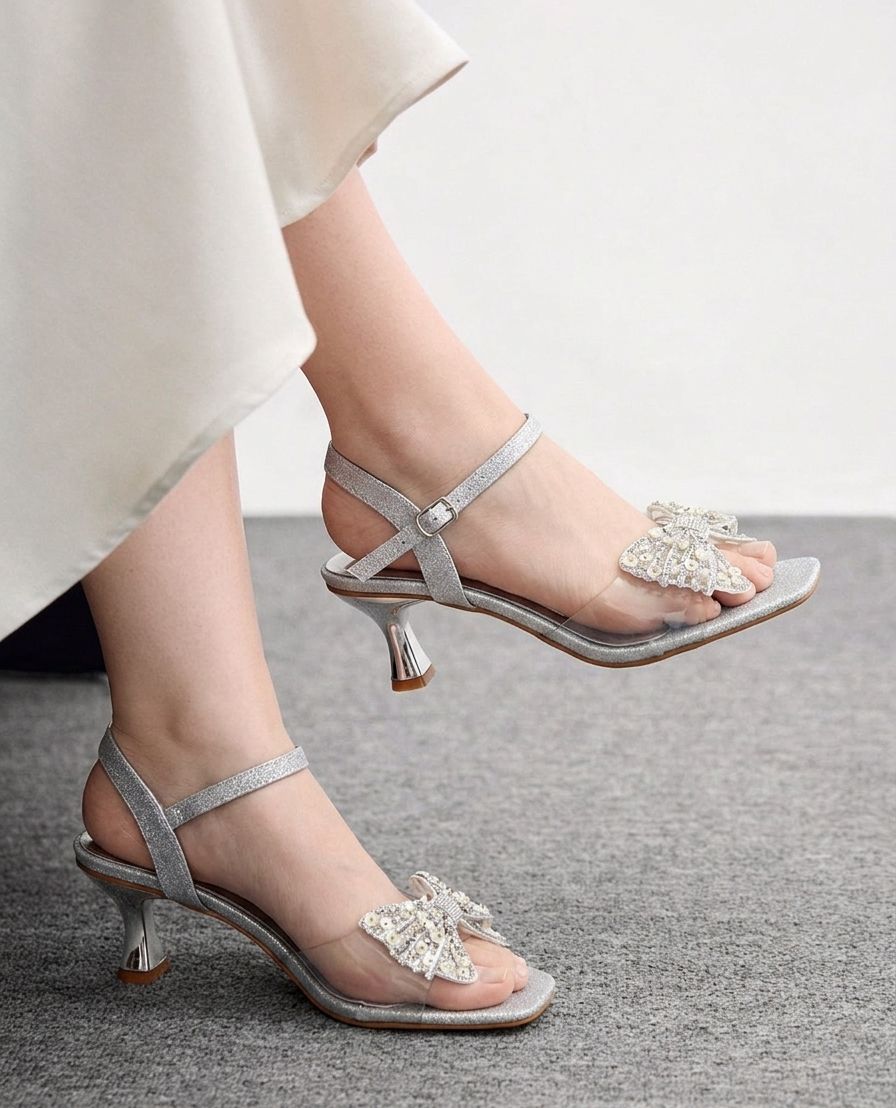 Silver high-heeled sandals with decorative straps on a neutral background